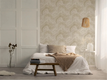 Marburg Struktura 45757 Bedroom scene showing a beige and gray wavy-pattern wallpaper used as a feature wall behind a low bed, with a rattan pendant light, small side table, and bench in view.