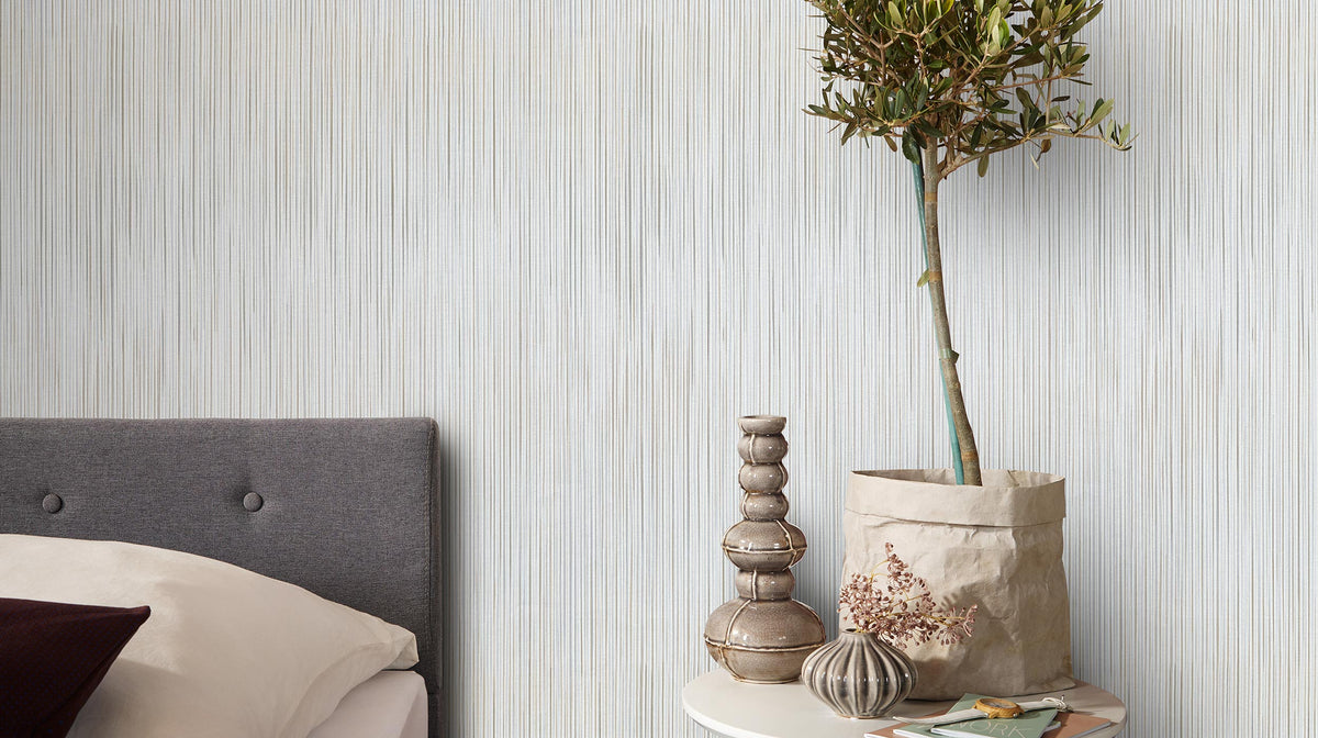 Room scene with Erismann Cameo 10533-37 vertical strié stripe wallpaper behind a bed and side table.