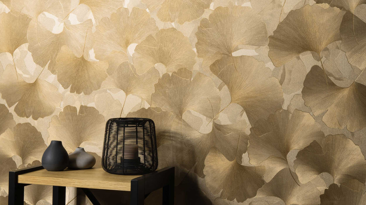Erismann Elysium 10470-30 beige and gold ginkgo leaf wallpaper behind a black console styled with ceramic vases and a lantern.