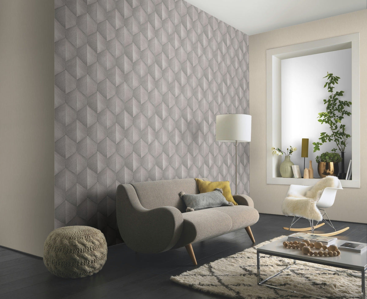 Erismann Fashion For Walls 4 10370-38 wallpaper lounge feature wall with geometric pattern behind curved sofa, floor lamp and rocking chair, low coffee table on a rug, plants in window alcove for a calm contemporary feel.