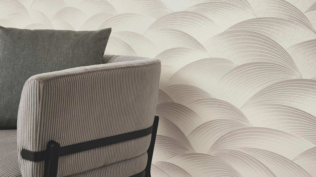 Erismann Fashion For Walls 4 10372-38 wallpaper lounge feature wall with curved layered pattern behind a ribbed upholstered armchair and cushion, calm modern mood.
