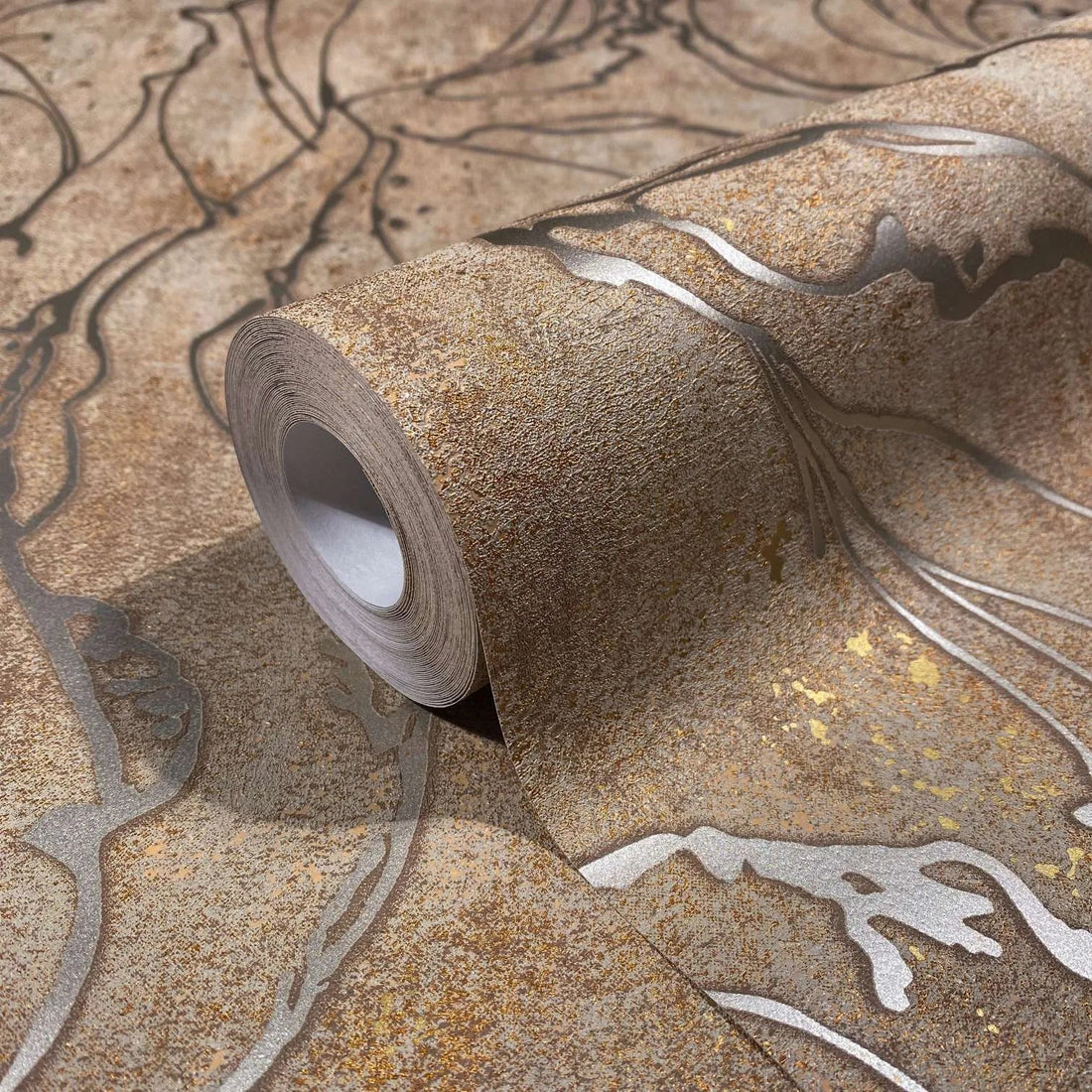 Marburg City Glow 34255 Textured brown wallpaper with flowing abstract leaf-like outlines behind a console vignette with a sculptural disc, dark glass vase, ceramic bowls, framed artwork, and a glass vase of dried grasses.