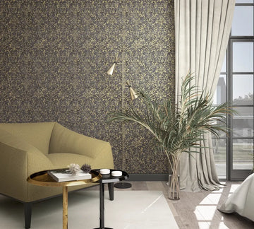 Marburg City Glow 34297 Living room scene with dark wallpaper covered in gold scrolling floral vines behind an armchair, two round side tables, a floor lamp, a tall plant in a glass vase, and a curtained window.