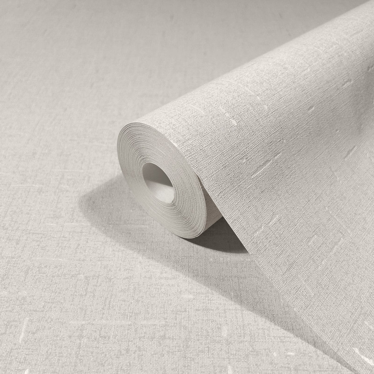 Marburg City Romance 35114 Angled roll of beige textured wallpaper with a fine linen-like weave and subtle light slubs, resting on matching unrolled wallpaper.