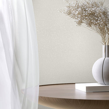 Marburg City Romance 35115 White textured wallpaper with a subtle crosshatch look behind a sheer curtain, a round wooden table, a spherical vase holding dried stems, and a closed book.