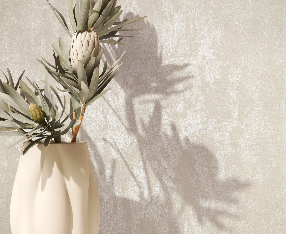 Marburg City Romance 35128 Close-up of light beige mottled wallpaper; a vase with leafy flower stems sits in front, casting shadows on the wall.