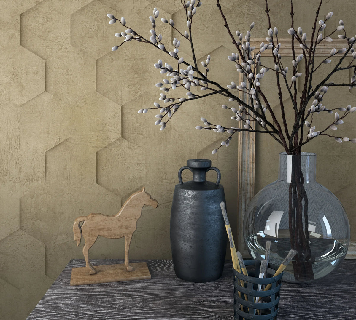 Marburg Loft Superior 34163 Brown wallpaper with a raised hexagonal pattern behind a tabletop vignette featuring a clear glass vase with branches, a dark vessel, a small wooden horse figure, a brush holder with paintbrushes, and a leaning frame.