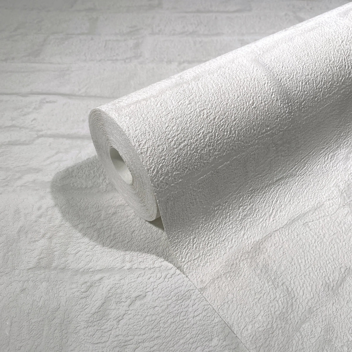 Marburg Loft Superior 34165 A white textured wallpaper roll resting on a matching unrolled sheet, showing an embossed rough surface with a subtle rectangular block pattern.