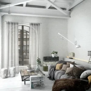 Marburg Loft Superior 34165 White brick effect wallpaper in a bright living room with an arched window, sheer curtains, a sofa with cushions, a coffee table, plants, a wall-mounted lamp, and exposed ceiling beams.