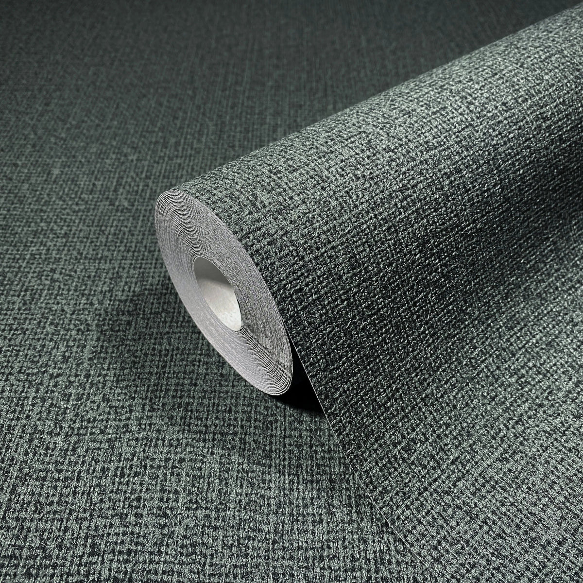Marburg Loft Superior 34180 Close-up of a dark green textured wallpaper roll resting on matching unrolled wallpaper, showing a fine crosshatch pattern.