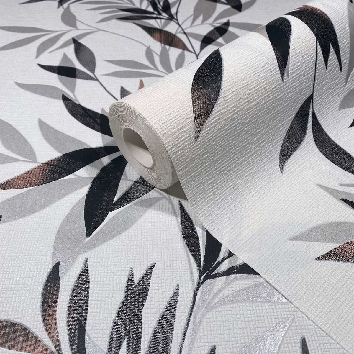 Marburg Mona 82458 Wallpaper roll on matching surface showing a black and gray leafy pattern on a white textured background.