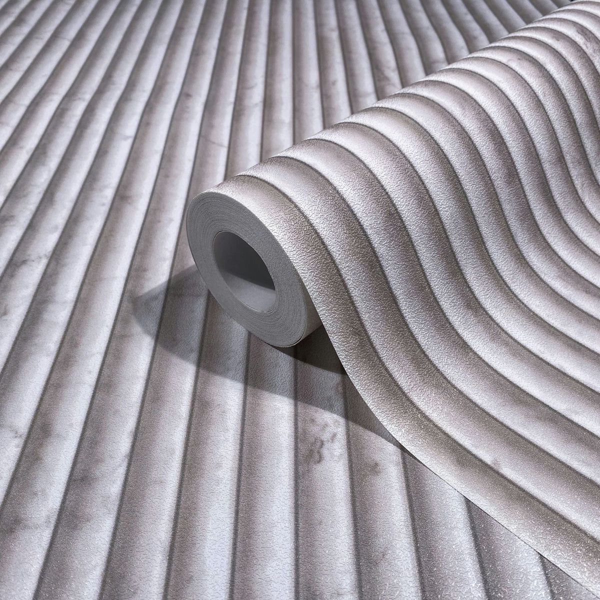 Marburg Mona 89004 Wallpaper roll on matching surface showing textured wavy ribbed stripes in beige and gray.