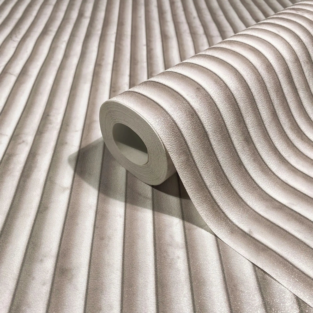 Marburg Mona 89006 Wallpaper roll on a matching surface showing a beige ribbed, softly wavy stripe pattern with a subtle 3D effect.