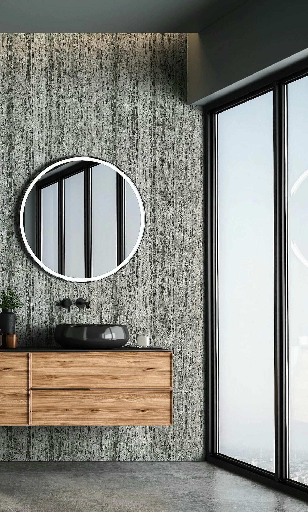 Marburg Travertino 33350 Beige and gray travertine-effect wallpaper with vertical striations behind a floating wood vanity. A round mirror, black vessel sink with wall-mounted faucet, and large floor-to-ceiling windows are visible.