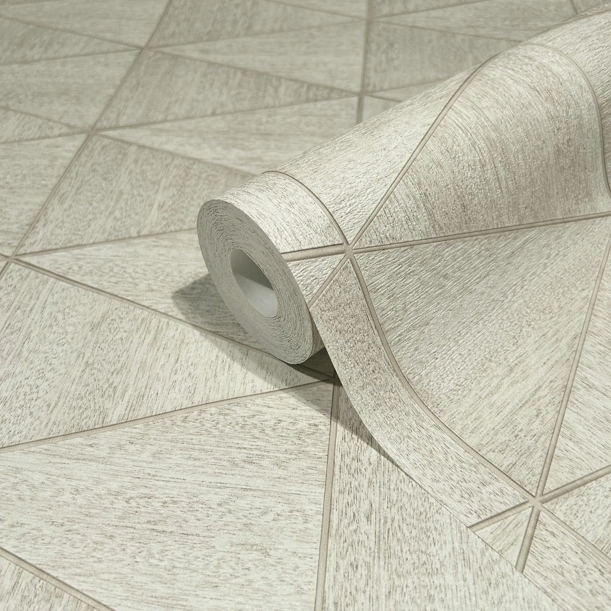 Marburg Travertino 33358 A wallpaper roll resting on matching wallpaper showing a light beige geometric pattern of intersecting lines with a subtle woodgrain texture.