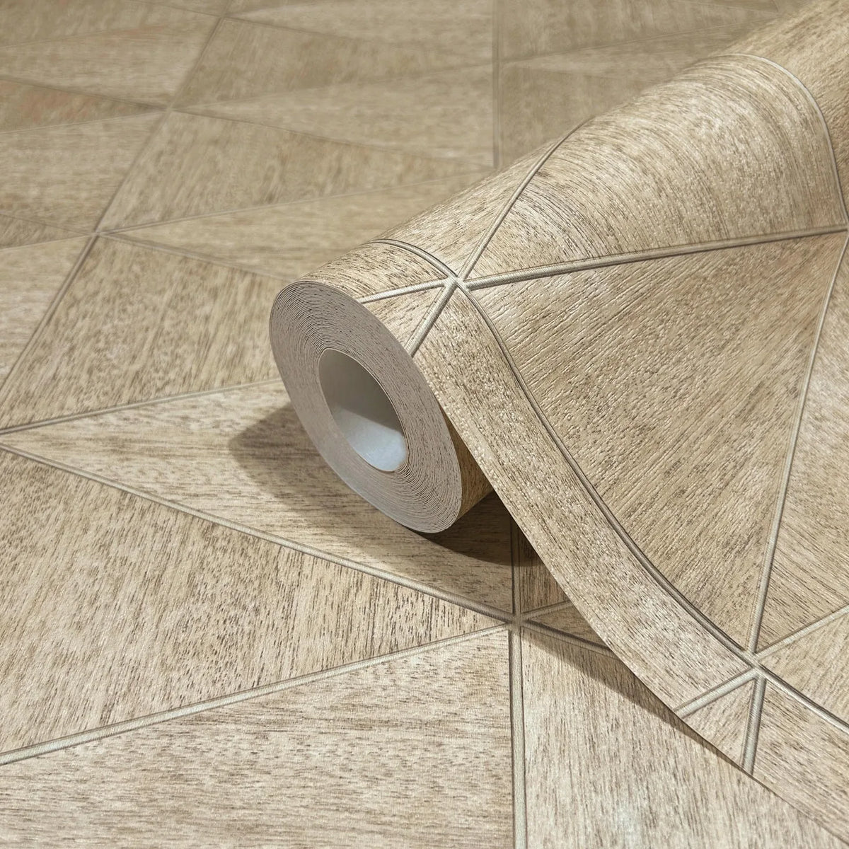 Marburg Travertino 33359 Wallpaper roll in beige and brown with a wood-textured geometric pattern of intersecting lines forming triangles, shown partially unrolled on a matching surface.