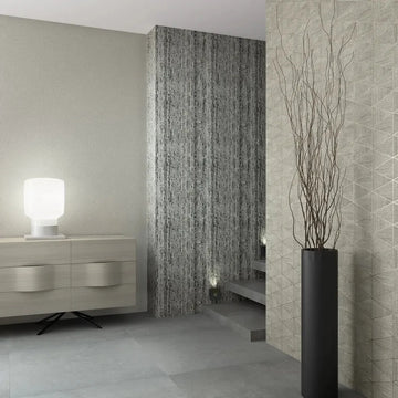 Marburg Travertino 33366 Modern stair area with a right wall in gray geometric triangle wallpaper, a center wall in dark vertically striated wallpaper, and a plain light gray wall. A low sideboard with a glowing table lamp sits on the left, open steps with small step lights lead up, и.