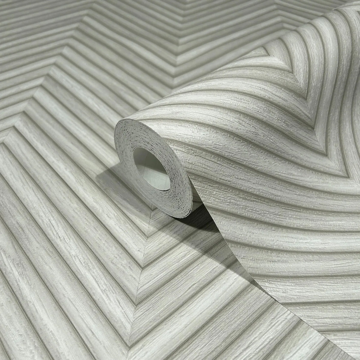 Marburg Travertino 33374 A wallpaper roll resting on an unrolled sheet showing a gray chevron-style pattern of diagonal ridged lines.