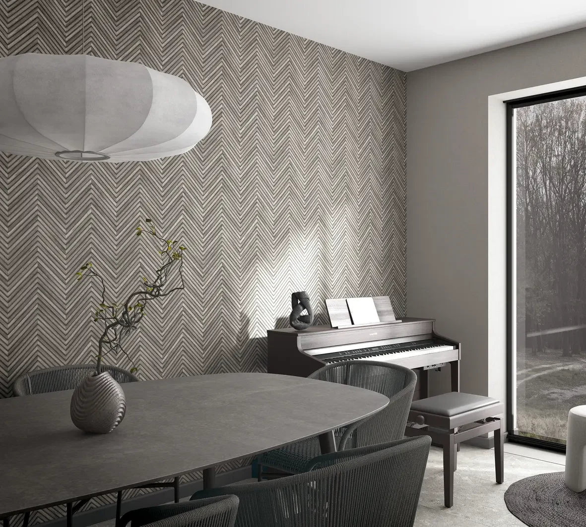 Marburg Travertino 33380 Gray chevron wallpaper on a feature wall in a dining area with a piano and bench, oval table with chairs, a pendant light, a small vase with branches, and a large window.