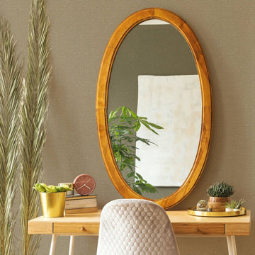 Marburg Travertino 33384 Textured beige wallpaper with subtle horizontal lines behind a wooden desk scene featuring an oval wood-framed mirror, upholstered chair, potted plants, a small clock, books, and a tray.