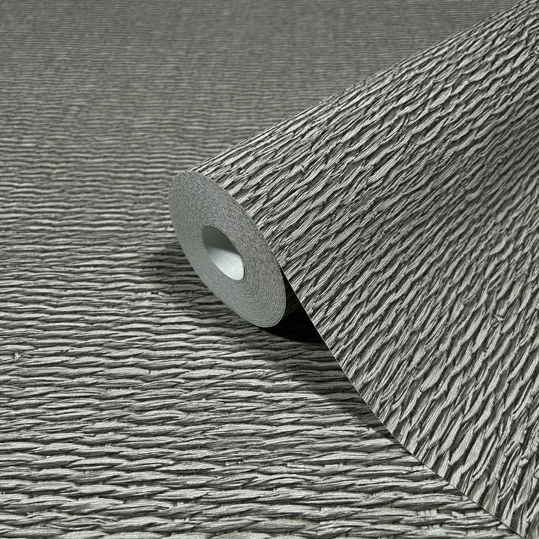Marburg Travertino 33386 Gray textured wallpaper with horizontal ripple lines shown above a light stone countertop and backsplash, with ceramic bowls, a small vase with dried stems, a dark plate, a woven placemat, and wood cabinets below.