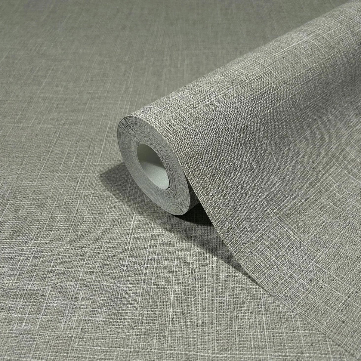 Marburg Travertino 33394 A gray wallpaper roll with a fine crosshatch texture, shown partially unrolled on the same patterned surface.